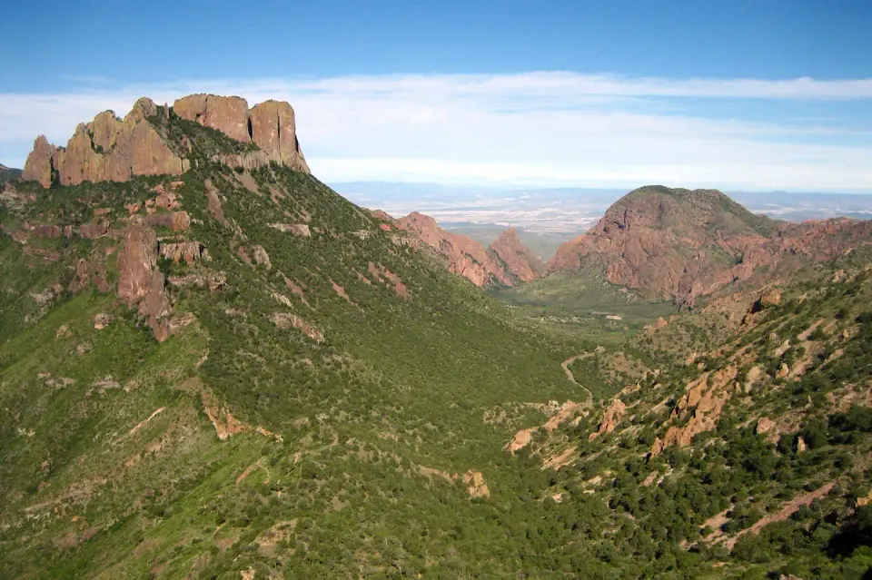 A view of Chisos Basin from the Lost Mine trail. Green vegetation with red mountains