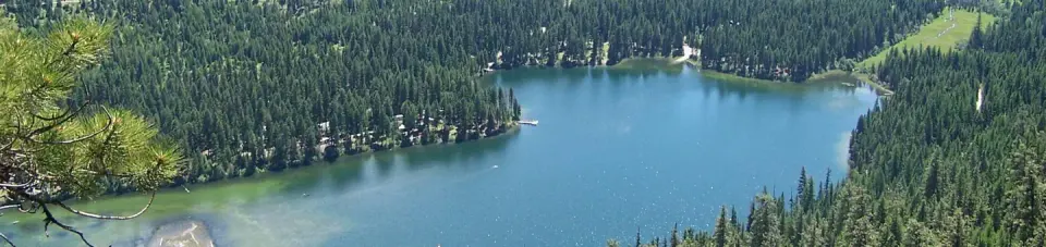 Aerial view of flat lake reflecting forested surroundings.